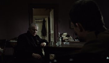 Movie still from “Blind Chance” (1987), directed by Krzysztof Kieslowski – An older man sitting at a table in front of a mirror; Medium shot, Over the shoulder angle