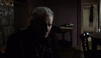Movie still from “Blind Chance” (1987), directed by Krzysztof Kieslowski – An older man sitting in a dark room; Close Up shot, Over the shoulder angle