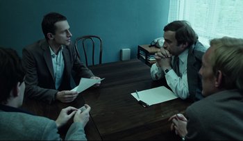 Movie still from “Blind Chance” (1987), directed by Krzysztof Kieslowski – A group of people sitting at a table with papers; Medium shot, Over the shoulder angle