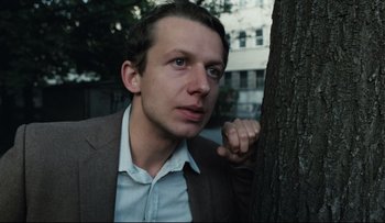 Movie still from “Blind Chance” (1987), directed by Krzysztof Kieslowski – A man leaning up against a tree outside; Close Up shot, Low angle