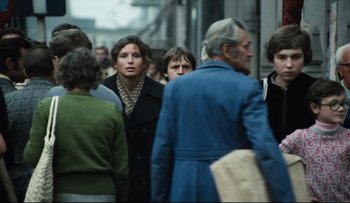 Movie still from “Blind Chance” (1987), directed by Krzysztof Kieslowski – A group of people walking down a street; Medium shot, Over the shoulder angle