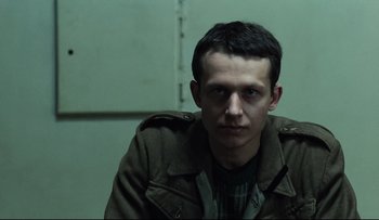 Movie still from “Blind Chance” (1987), directed by Krzysztof Kieslowski – A man in a jacket is sitting in front of a wall; Close Up shot, Low angle