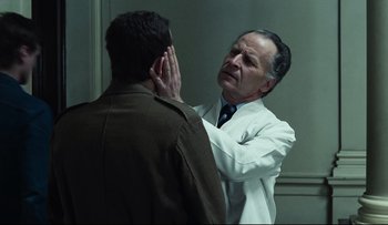 Movie still from “Blind Chance” (1987), directed by Krzysztof Kieslowski – An older man in a white lab coat is looking at a younger man; Medium shot, Over the shoulder angle