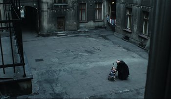 Movie still from “Blind Chance” (1987), directed by Krzysztof Kieslowski – A woman sitting on the ground with a baby in a stroller; Extreme Wide shot, High angle