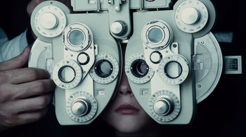Movie still from “Blindness” (2008), directed by Fernando Meirelles – A woman is looking through a phoropter; Extreme Close Up shot, Overhead angle