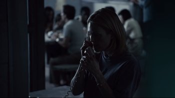 Movie still from “Blindness” (2008), directed by Fernando Meirelles – A woman talking on a phone while sitting in a room; Medium shot, Over the shoulder angle