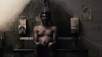 Movie still from “Blindness” (2008), directed by Fernando Meirelles – A man sitting under a shower in a bathroom; Medium shot, Overhead angle
