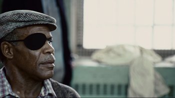 Movie still from “Blindness” (2008), directed by Fernando Meirelles – An older man wearing a hat and eye patch; Close Up shot, Over the shoulder angle
