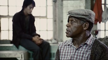 Movie still from “Blindness” (2008), directed by Fernando Meirelles – An older man wearing a hat and sitting in front of a woman; Close Up shot, Over the shoulder angle
