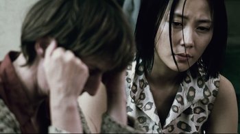 Movie still from “Blindness” (2008), directed by Fernando Meirelles – A woman and a young man sitting next to each other; Close Up shot, Over the shoulder angle