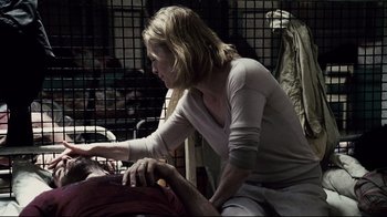 Movie still from “Blindness” (2008), directed by Fernando Meirelles – A woman sitting on top of a man in a room; Medium shot, Over the shoulder angle