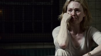 Movie still from “Blindness” (2008), directed by Fernando Meirelles – A woman sitting in front of a fence with her hand on her face; Close Up shot, High angle