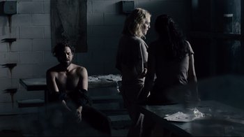Movie still from “Blindness” (2008), directed by Fernando Meirelles – A group of people standing in a dark room; Wide shot, Over the shoulder angle