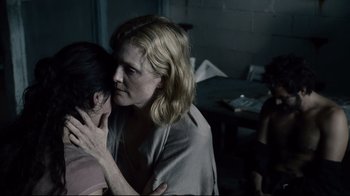 Movie still from “Blindness” (2008), directed by Fernando Meirelles – A woman is hugging another woman in a dark room; Close Up shot, Over the shoulder angle