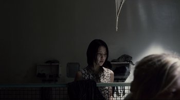 Movie still from “Blindness” (2008), directed by Fernando Meirelles – A young woman is standing in a dark room; Medium shot, Over the shoulder angle
