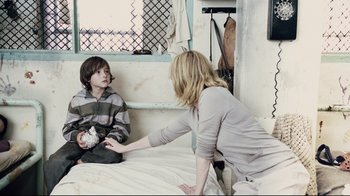 Movie still from “Blindness” (2008), directed by Fernando Meirelles – A young boy sitting on a bed talking to an older woman; Medium shot, Over the shoulder angle