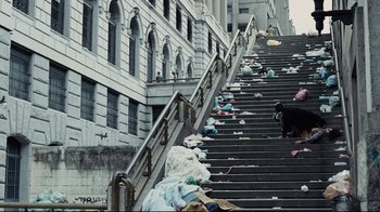 Movie still from “Blindness” (2008), directed by Fernando Meirelles – A bunch of garbage is on the steps of a building; Extreme Wide shot, Low angle