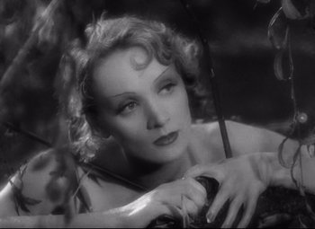Movie still from “Blonde Venus” (1932), directed by Josef von Sternberg – An old black and white photo of a woman holding an umbrella; Close Up shot, High angle