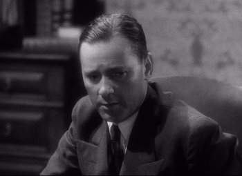 Movie still from “Blonde Venus” (1932), directed by Josef von Sternberg – A man sitting in a chair wearing a suit and tie; Close Up shot, Low angle