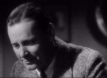 Movie still from “Blonde Venus” (1932), directed by Josef von Sternberg – A man in a suit and tie sitting in a room; Close Up shot, Low angle