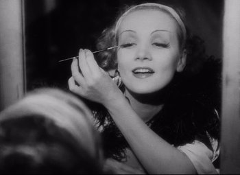 Movie still from “Blonde Venus” (1932), directed by Josef von Sternberg – A woman putting makeup on her face in a black - and - white photo; Close Up shot, Low angle
