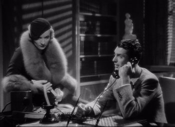 Movie still from “Blonde Venus” (1932), directed by Josef von Sternberg – A man and a woman sitting at a table talking on the phone; Medium shot, High angle