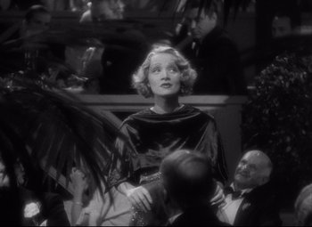 Movie still from “Blonde Venus” (1932), directed by Josef von Sternberg – An old photo of a woman in a black dress; Medium shot, Over the shoulder angle