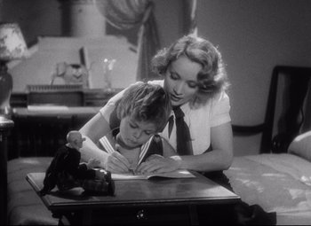Movie still from “Blonde Venus” (1932), directed by Josef von Sternberg – A woman and a child sitting at a desk; Medium shot, High angle