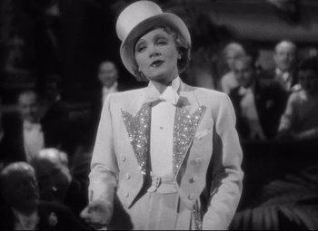 Movie still from “Blonde Venus” (1932), directed by Josef von Sternberg – A black and white photo of a woman in a suit and top hat; Medium shot, Low angle