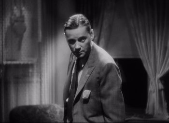 Movie still from “Blonde Venus” (1932), directed by Josef von Sternberg – A man wearing a suit and tie standing in front of a window; Close Up shot, Low angle