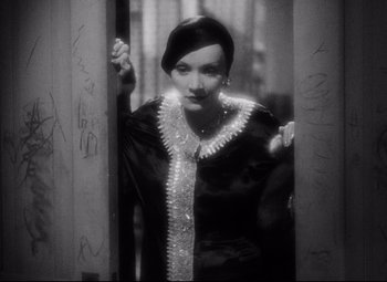 Movie still from “Blonde Venus” (1932), directed by Josef von Sternberg – A woman in a black dress standing in a doorway; Close Up shot, Low angle