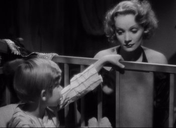Movie still from “Blonde Venus” (1932), directed by Josef von Sternberg – A young child reaching for a woman in a baby crib; Close Up shot, High angle