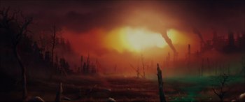 The sun is setting over a field of dead trees