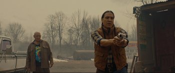 Movie still from “Blood Quantum” (2019), directed by Jeff Barnaby – A man holding a gun while standing in a field; Medium shot, Over the shoulder angle