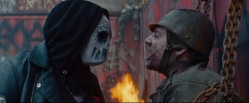 Movie still from “Blood Quantum” (2019), directed by Jeff Barnaby – Two people dressed up in scary costumes face each other; Close Up shot, Low angle