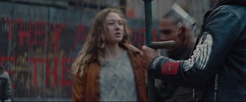 Movie still from “Blood Quantum” (2019), directed by Jeff Barnaby – A woman in a brown jacket holding onto a green pole; Medium shot, Over the shoulder angle