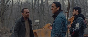 Movie still from “Blood Quantum” (2019), directed by Jeff Barnaby – Two men standing next to each other near a forest; Medium shot, Over the shoulder angle