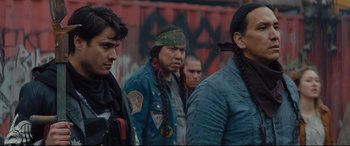 Movie still from “Blood Quantum” (2019), directed by Jeff Barnaby – A group of men standing next to each other on the street; Medium shot, Over the shoulder angle