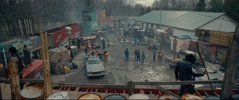 Movie still from “Blood Quantum” (2019), directed by Jeff Barnaby – A group of people standing in a parking lot next to a car; Extreme Wide shot, High angle
