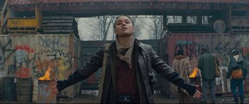 Movie still from “Blood Quantum” (2019), directed by Jeff Barnaby – A woman in a leather jacket standing in front of a building; Medium shot, Low angle