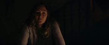 Movie still from “Blood Quantum” (2019), directed by Jeff Barnaby – A young woman in a dark room looking at the camera; Close Up shot, Low angle