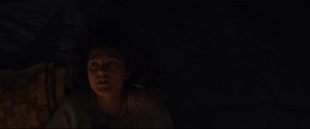 Movie still from “Blood Quantum” (2019), directed by Jeff Barnaby – A woman is laying down in the dark; Close Up shot, Overhead angle