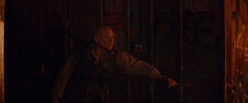 Movie still from “Blood Quantum” (2019), directed by Jeff Barnaby – A man in military fatigues holding a gun in front of a wall; Medium shot, Low angle