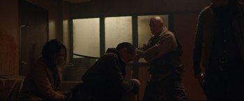 Movie still from “Blood Quantum” (2019), directed by Jeff Barnaby – A man is standing next to another man in a dark room; Medium shot, Over the shoulder angle
