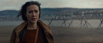 Movie still from “Blood Quantum” (2019), directed by Jeff Barnaby – A woman standing in front of a fence looking at the camera; Close Up shot, Over the shoulder angle