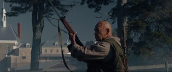Movie still from “Blood Quantum” (2019), directed by Jeff Barnaby – A bald man with a rifle in his hands; Medium shot, Low angle