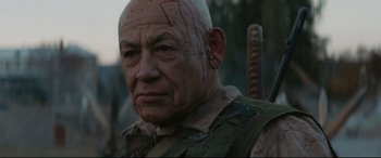 Movie still from “Blood Quantum” (2019), directed by Jeff Barnaby – A bald man with blood all over his face; Close Up shot, Over the shoulder angle