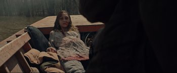 Movie still from “Blood Quantum” (2019), directed by Jeff Barnaby – A woman with a bandage on her face is lying on the ground in front of a brown bear; Medium shot, Over the shoulder angle