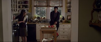 Movie still from “The Amazing Spider-Man” (2012), directed by Marc Webb – A man sitting in a kitchen next to a counter; Wide shot, High angle
