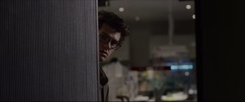 Movie still from “The Amazing Spider-Man” (2012), directed by Marc Webb – A man with glasses leaning against a wall in a room; Close Up shot, Over the shoulder angle